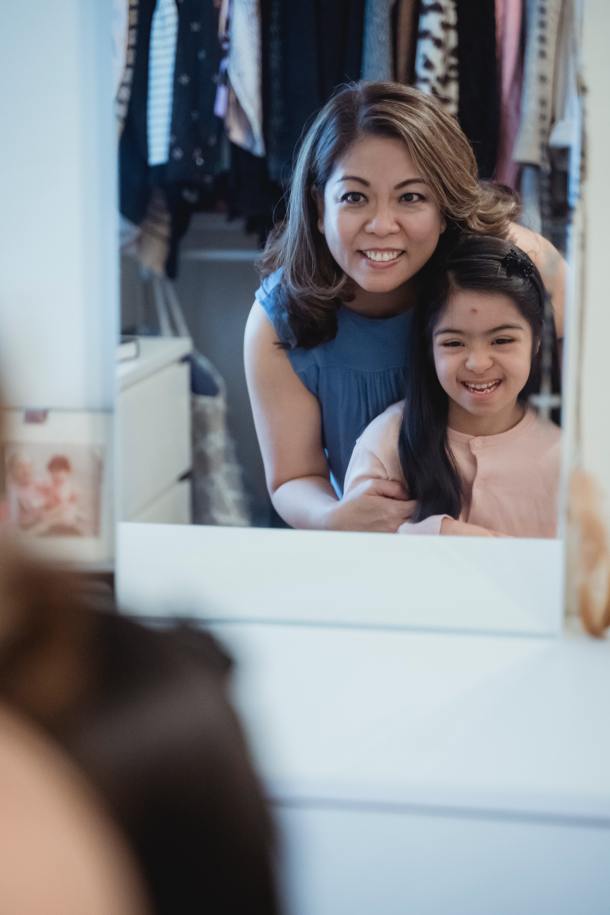 Young girl with mom both looking in the mirror.